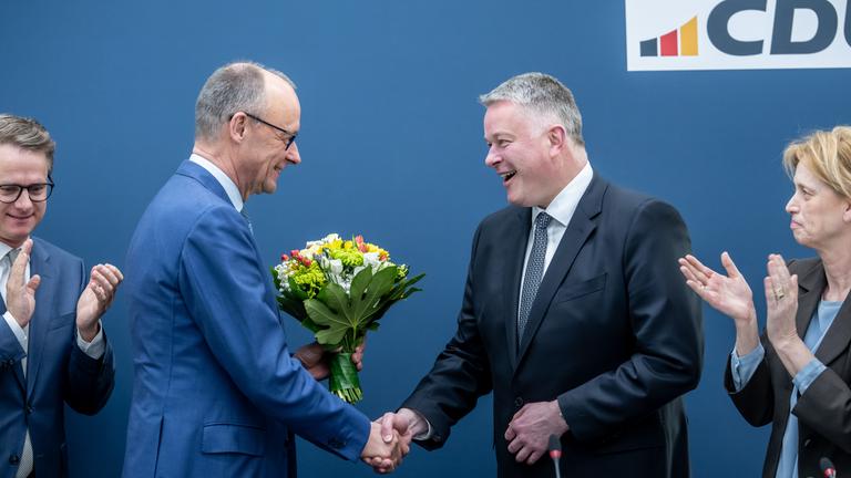 Gordon Schnieder (CDU) erhält Blumen von Bundeskanzler Friedrich Merz.