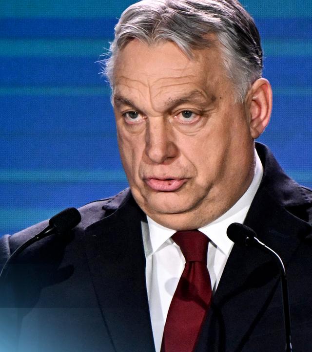 Ungarns Ministerpräsident Viktor Orbán mit erhobenen Händen gestikulierend vor einem blauen Hintergrund.