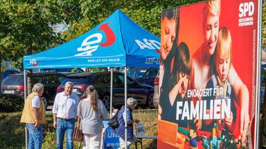 Leif-Erik Holm (2.v.l) , Ministerpräsidentenkandidat der AfD für die Landtagswahl in Mecklenburg-Vorpommern und Landesvorsitzender der Partei in Mecklenburg-Vorpommern, spricht an einem Informationsstand der Partei mit Passanten. Im Vordergrund ist ein Wahlplakat der SPD zu sehen