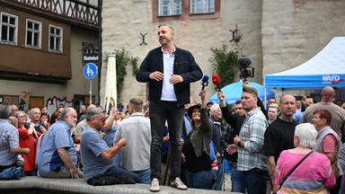 Ulrich Siegmund, Spitzenkandidat der AfD in Sachsen-Anhalt, spricht von einem Brunnen auf dem Marktplatz in Sangerhausen zu den Besuchern eines AfD Wahlkampfstandes.