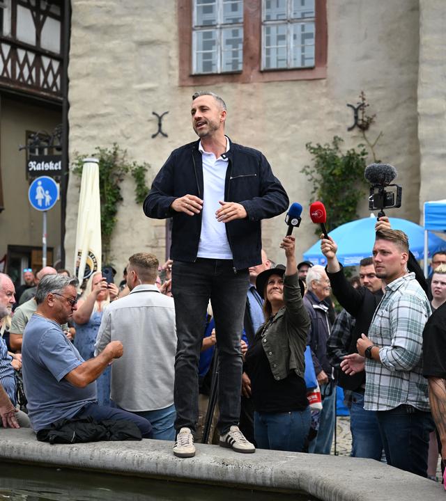 Ulrich Siegmund, Spitzenkandidat der AfD in Sachsen-Anhalt, spricht von einem Brunnen auf dem Marktplatz in Sangerhausen zu den Besuchern eines AfD Wahlkampfstandes.