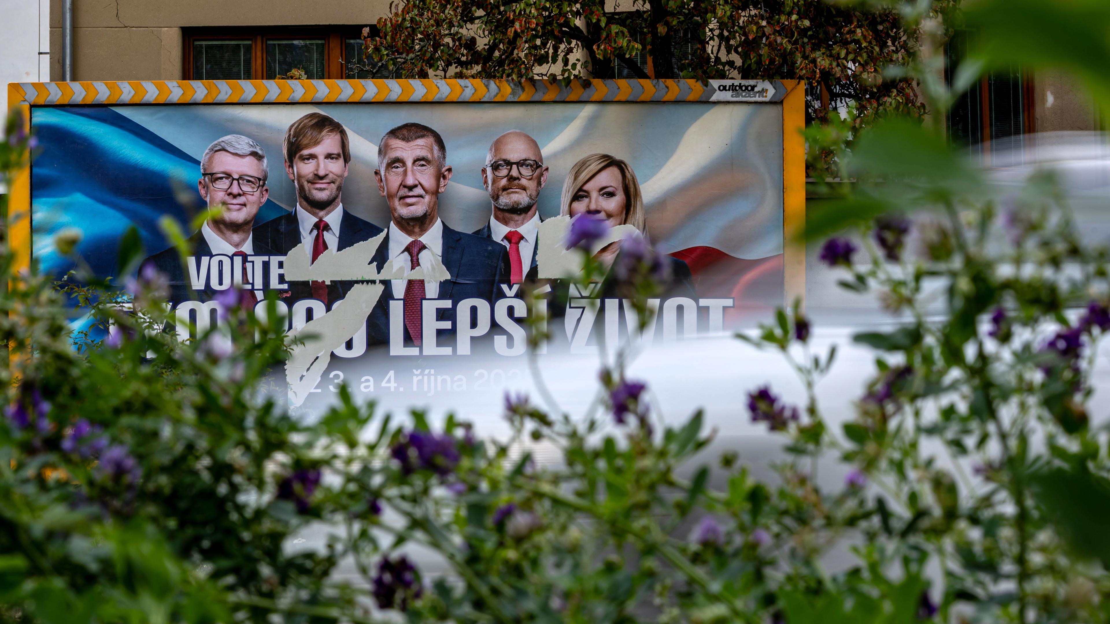 Vorbeifahrendes Auto verschwommen vor einem Wahlplakat von Andrej Babiš in Tschechien.