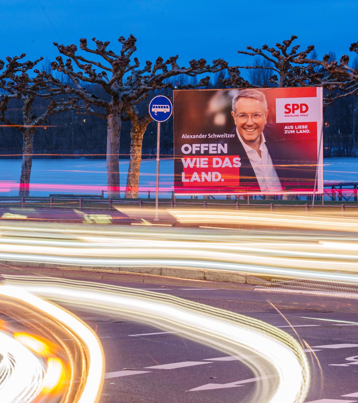 23.02.2026, Rheinland-Pfalz, Mainz: Vorbeifahrende Fahrzeuge erzeugen auf der Rheinallee Lichtstreifen vor den Wahlplakaten von Gordon Schnieder (l-r, CDU), CDU-Landeschef und Spitzenkandidat seiner Partei, mit Isabell Rahms (CDU), Landtagskandidatin ihrer Partei für Mainz zur anstehenden Landtagswahl, und Alexander Schweitzer (SPD), Ministerpräsident von Rheinland-Pfalz und Spitzenkandidat der SPD. 