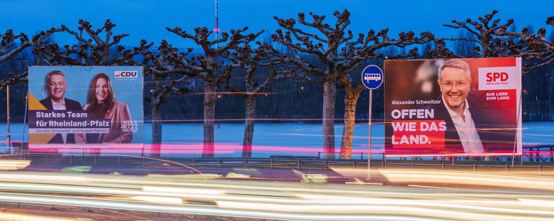 23.02.2026, Rheinland-Pfalz, Mainz: Vorbeifahrende Fahrzeuge erzeugen auf der Rheinallee Lichtstreifen vor den Wahlplakaten von Gordon Schnieder (l-r, CDU), CDU-Landeschef und Spitzenkandidat seiner Partei, mit Isabell Rahms (CDU), Landtagskandidatin ihrer Partei für Mainz zur anstehenden Landtagswahl, und Alexander Schweitzer (SPD), Ministerpräsident von Rheinland-Pfalz und Spitzenkandidat der SPD. 
