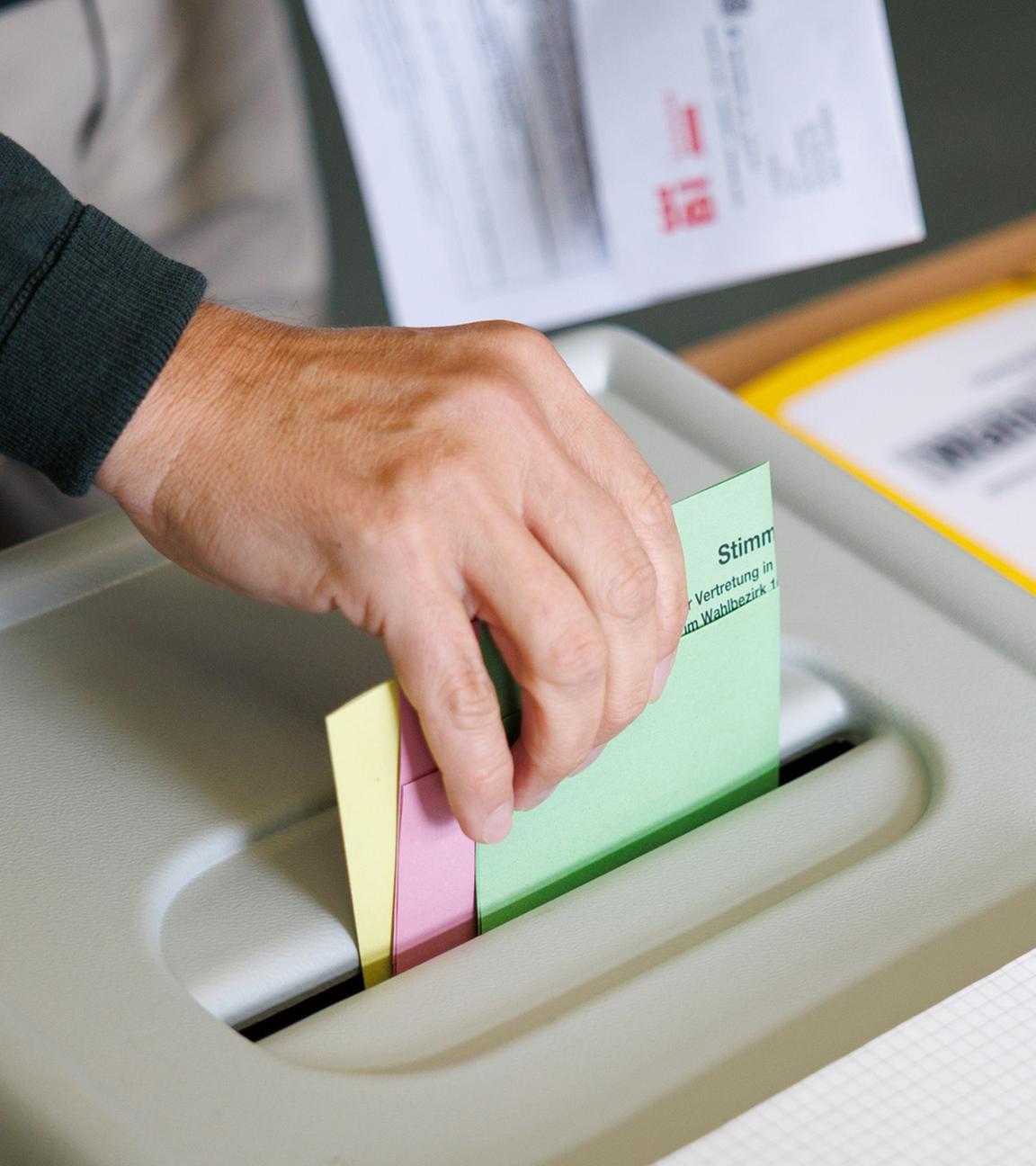 Ein Wähler wirft am 14.09.2025 seine Stimmzettel in eine Wahlurne in einem Wahlraum in der Realschule Brackwede bei den Kommunalwahlen in Nordrhein-Westfalen.