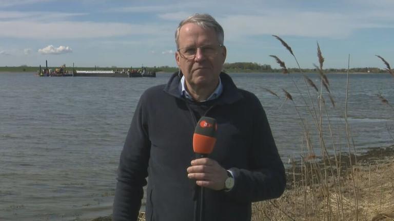 ZDF-Reporter Mosebach am Strand. Im Hintergrund ist der Frachtkahn der Rettungsaktion auf dem Wasser zu sehen.