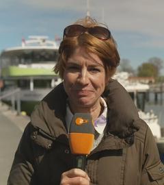 ZDF-Reporterin Anne Stadtfeld an einem Steg mit einer Bootsfähre im Hintergrund.