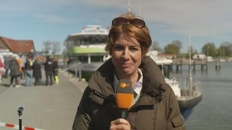 ZDF-Reporterin Anne Stadtfeld an einem Steg mit einer Bootsfähre im Hintergrund.