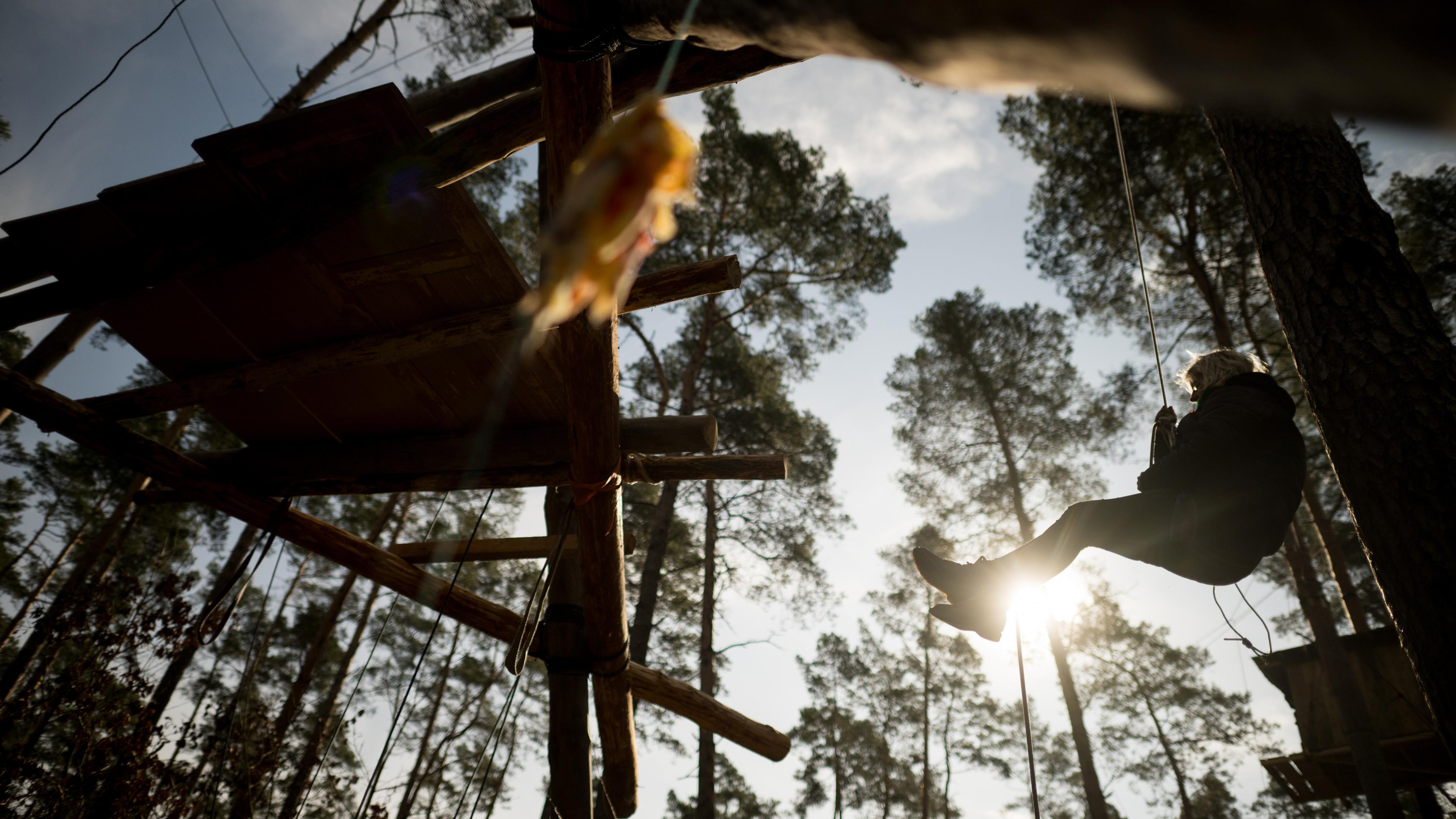Eine Aktivistin seilt sich in einem Camp der Initiative "Tesla stoppen" in einem Kiefernwald nahe der Tesla-Gigafactory Berlin-Brandenburg von einem Hochsitz ab am 15.03.2024.