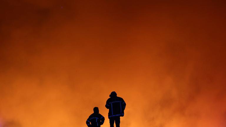 Feuerwehrleute beobachten am 22. 7. 2026 einen Waldbrand in Le Porge im Südwesten Frankreichs.