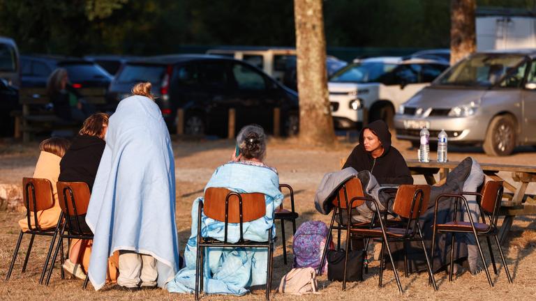 Evakuierte Anwohner sitzen in Schlafsäcken außerhalb der Gerard-Blanc-Festivalhalle in Le Porge im Südwesten Frankreichs.