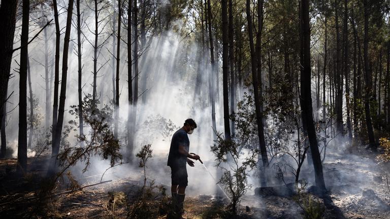 Ein freiwilliger Helfer aus der Region unterstützt französische Feuerwehrleute bei Löscharbeiten während eines Waldbrandes in Claouey im Südwesten Frankreichs am 28. Juli 2026.