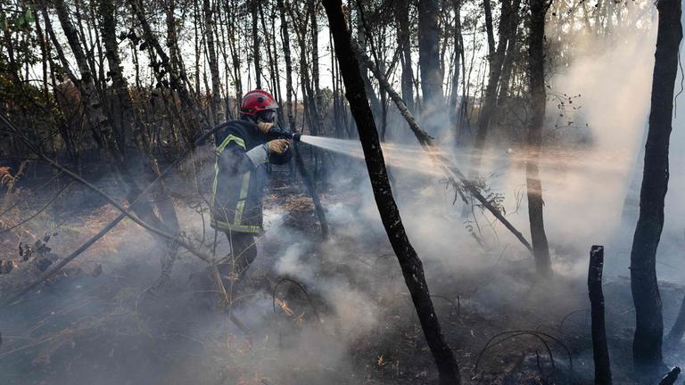 Ein Feuerwehrmann besprüht nach einem Waldbrand in Saint-Just im Westen Frankreichs ein verbranntes Waldgebiet mit Wasser.