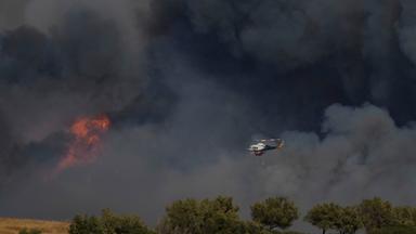 Griechenland, Keratea: Ein Hubschrauber fliegt durch den Rauch eines Brandes in Keratea, einem Außenbezirk von Athen.