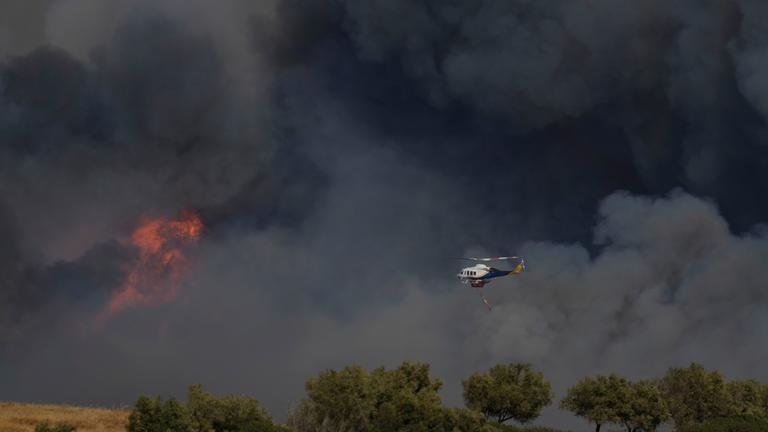 Griechenland, Keratea: Ein Hubschrauber fliegt durch den Rauch eines Brandes in Keratea, einem Außenbezirk von Athen.