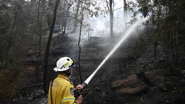 Ein Feuerwehrmann löscht mit einem Wasserschlauch einen Buschbrand, der sich im Gebiet von Koolewong an der Central Coast in New South Wales (NSW), Australien, ausbreitet (06. Dezember 2025).