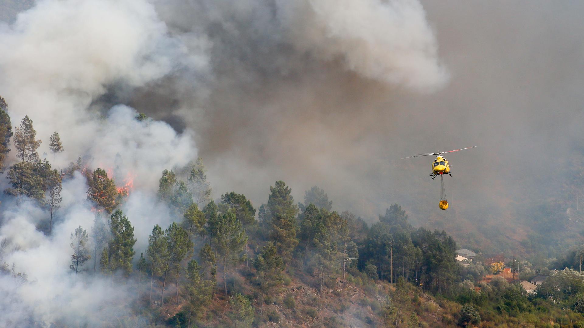 Ein Hubschrauber transportiert Wasser zum Löschen des Feuers in Quiroga.