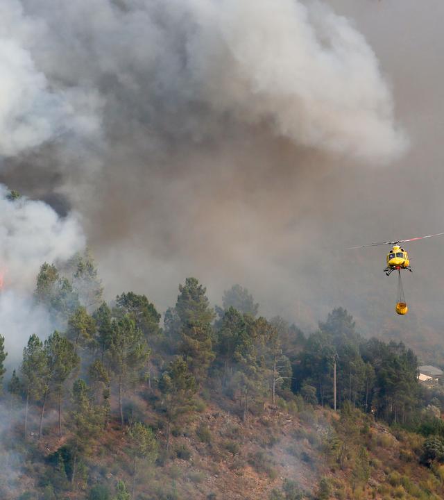 Ein Hubschrauber transportiert Wasser zum Löschen des Feuers in Quiroga.