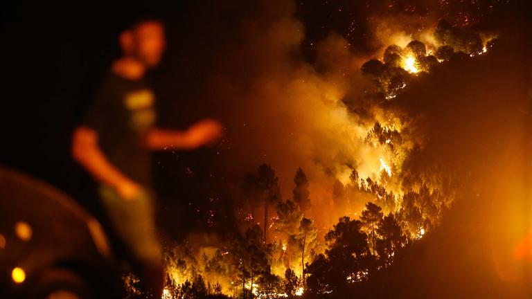 Ein Mann geht in der Nähe des Brandes von Quiroga. 