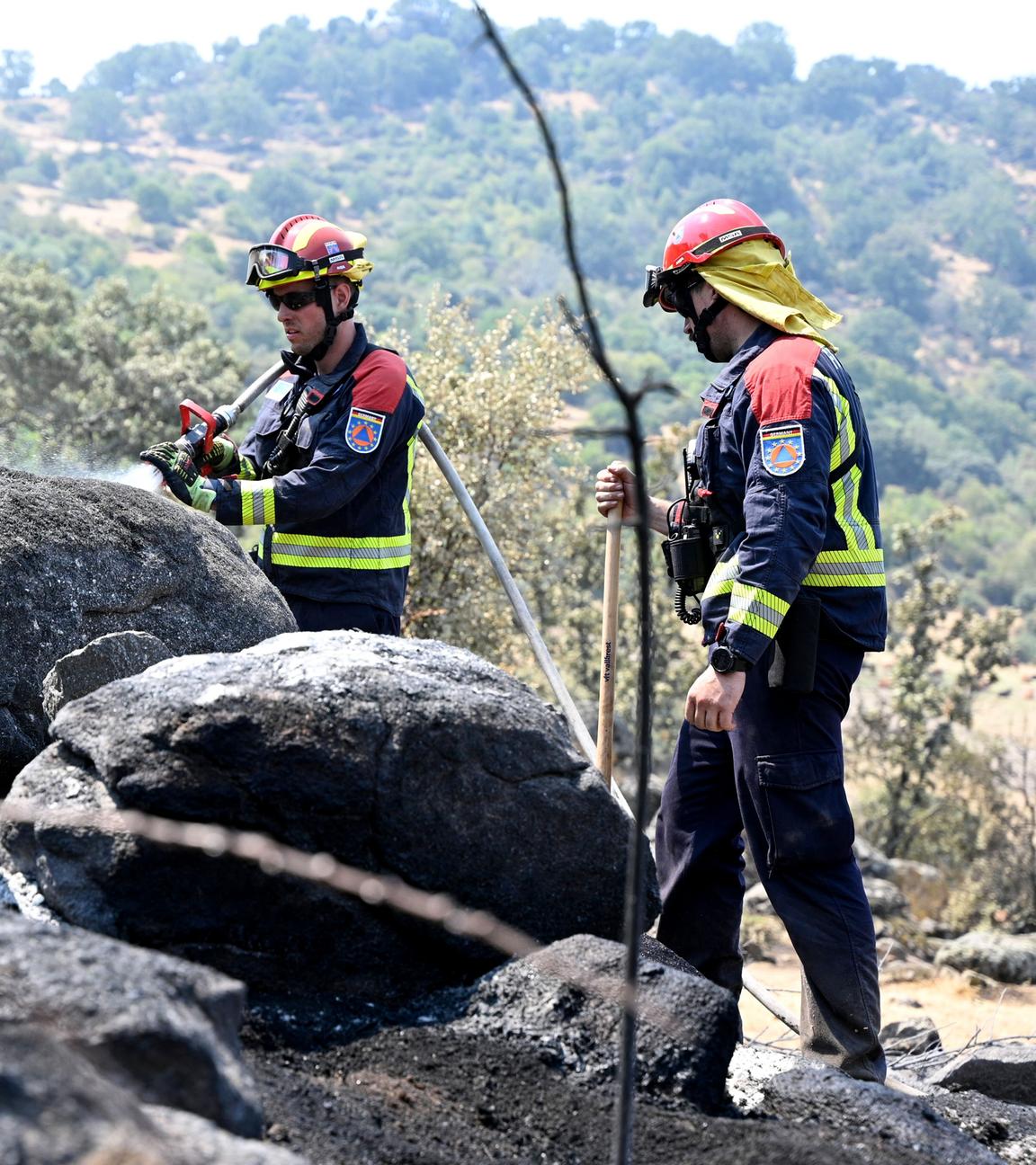 Deutsche Feuerwehrleute spritzen in der Region Extremadura Wasser auf einen bereits abgebrannten Bereich, suchen nach möglichen Glutnestern.