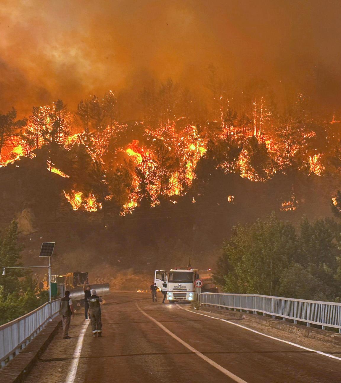 Eine Straße im Nordwesten der Türkei, im Hintergrund lodert ein großer Waldbrand.
