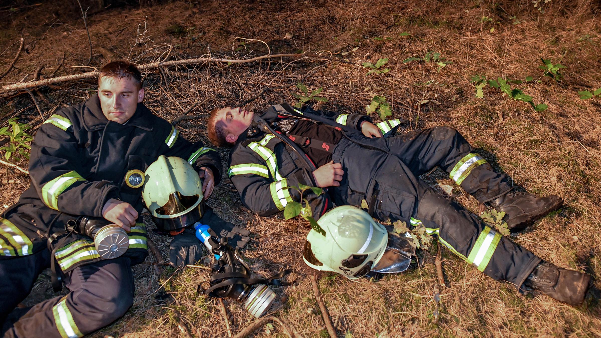 Erschöpfte Feuerwehrleute ruhen sich nach einem Einsatz aus.