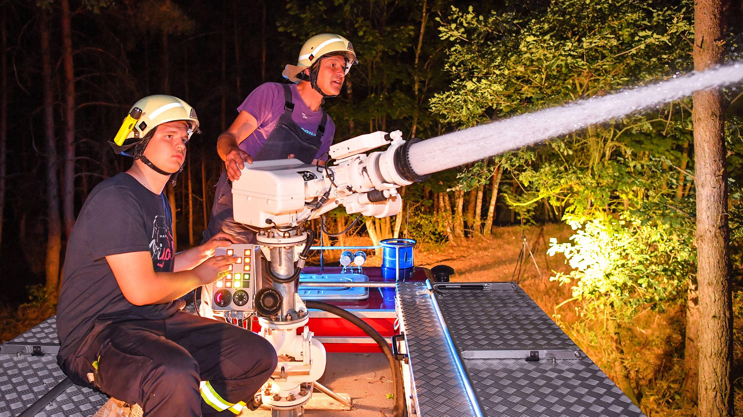 Vom Dach ihres Fahrzeugs aus löschen Feuerwehrleute einen Brand nahe Klausdorf.