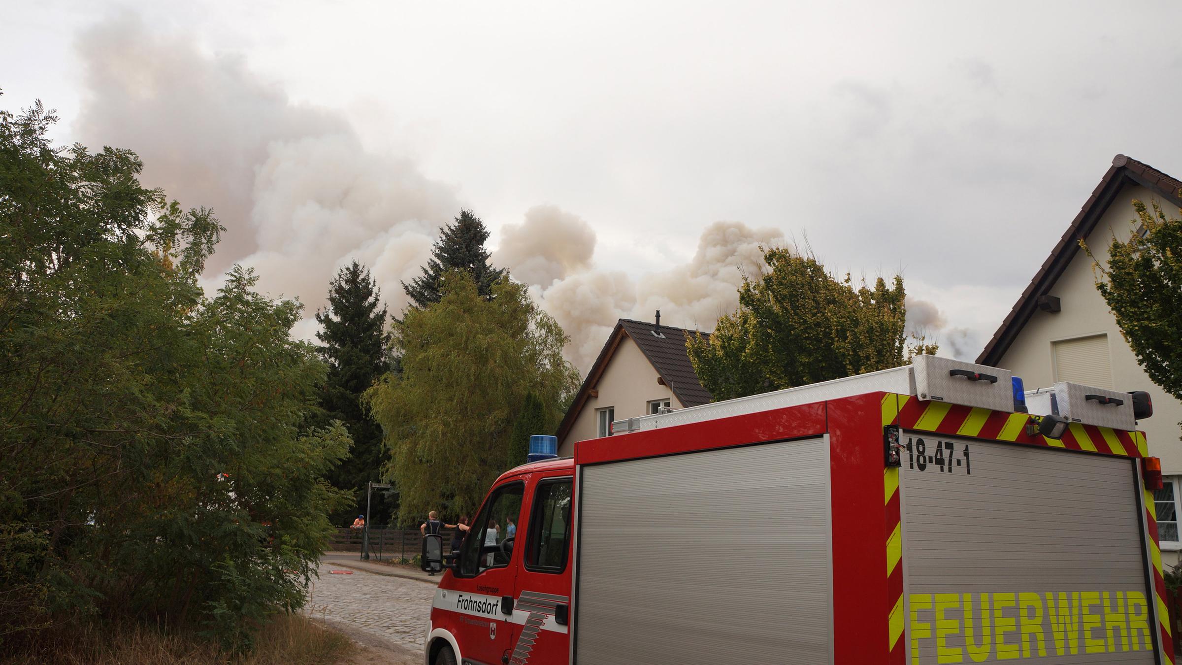 Das Feuer hat sich bis Frohnsdorf ausgebreitet. Rauch steigt neben einem Haus am Ortsrand auf.