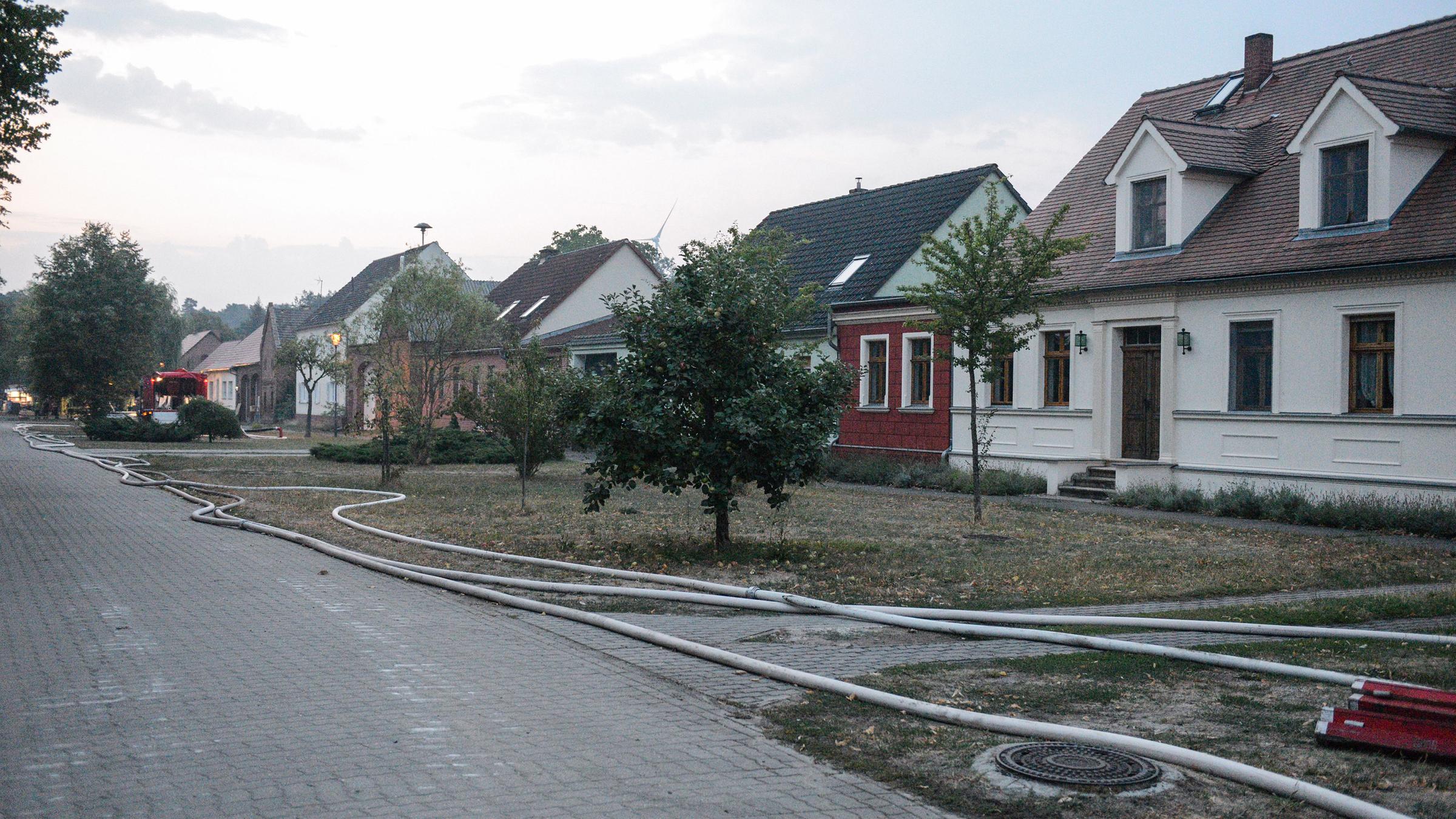Nach der Evakuierung von Klausdorf liegen Löschschläuche an einer Straße.