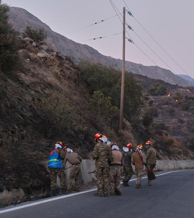Feuerwehrleute inspizieren einen verbrannten Hang nach einem Waldbrand in der Region Rethymno auf der südgriechischen Insel Kreta. 