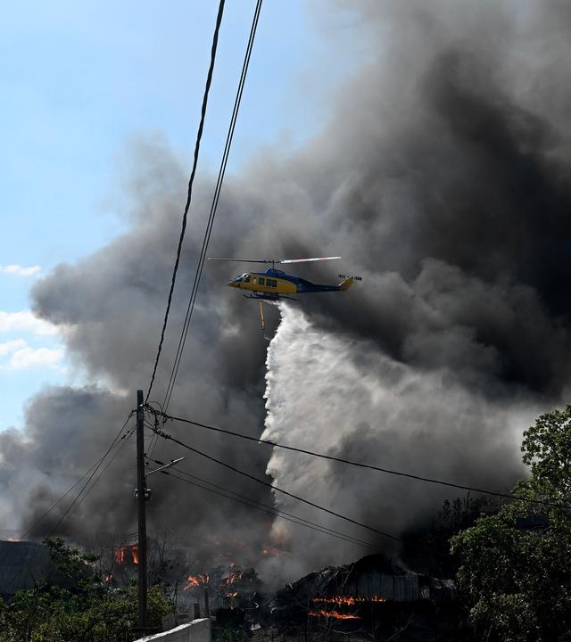 Ein Hubschrauber wirft Wasser über einen Waldbrand am Stadtrand der im Norden Griechenlands gelegenen Stadt Thessaloniki ab. 