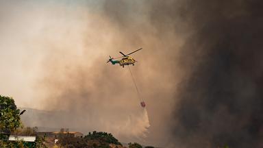 10.07.2026, Spanien, Los Gallardos (Almeria): Ein Löschhubschrauber wirft über dem Waldbrand Wasser ab. Der Waldbrand in der Provinz Almería gilt als der bisher tödlichste des 21. Jahrhunderts in Spanien. Unter den Opfern befinden sich mutmaßlich auch Ausländer. 