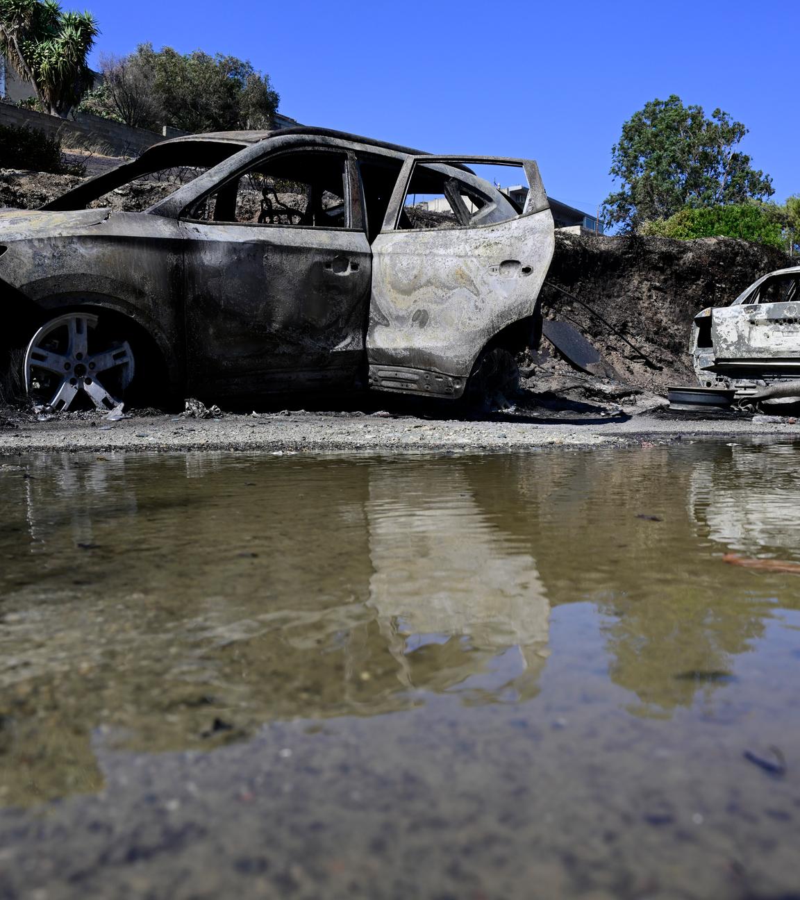Ausgebrannte Autos spiegeln sich im Wasser nach einem Waldbrand in dem Dorf südöstlich von Athen. 