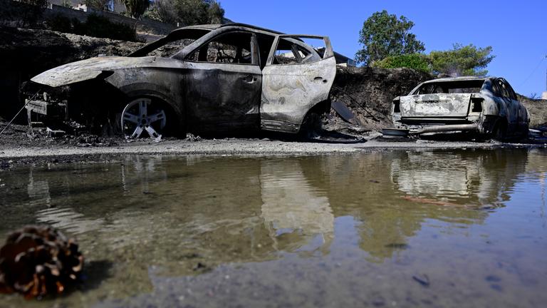 Ausgebrannte Autos spiegeln sich im Wasser nach einem Waldbrand in dem Dorf südöstlich von Athen. 