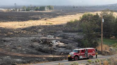 Feuerwehrleute beladen ihr Fahrzeug, nachdem sie am 23.08.2026 im amerikanischen Reno, Nevada, zu einem Brand in einem Gebäude im Zuge des „Hawk Fire“ ausgerückt waren. 