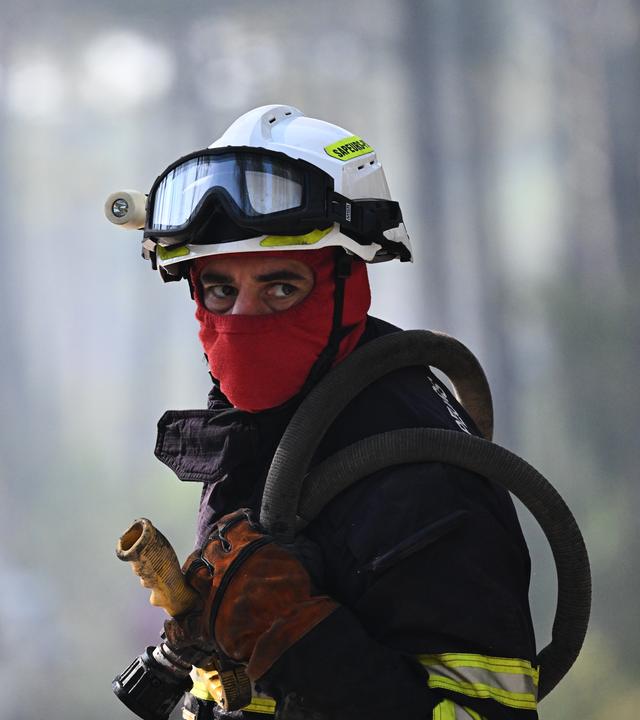 Ein Feuerwehrmann arbeitet bei den Löscharbeiten von einem Waldbrand in der französischen Gemeinde Claouey. 