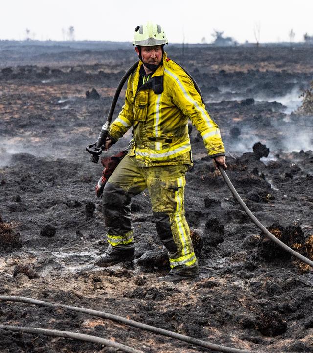 Ein Feuerwehrmann löscht Glutnester im schwelenden Boden in der Nähe des Signal de Botrange am Ort des Brandes im Naturschutzgebiet Hohes Venn.