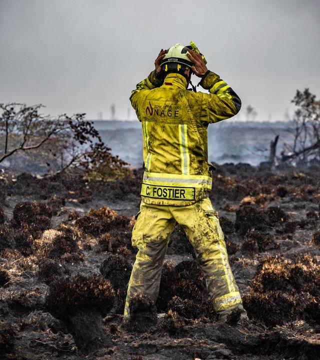 Ein Feuerwehrmann steht am Brandort im Naturschutzgebiet Hohes Venn, aufgenommen am 18.08.2026