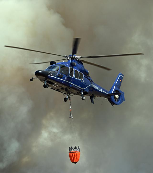 in Helikopter nimmt Wasser in Löschwasser-Außenlastbehältern zum Einsatz beim Waldbrand im Hürtgenwald auf.