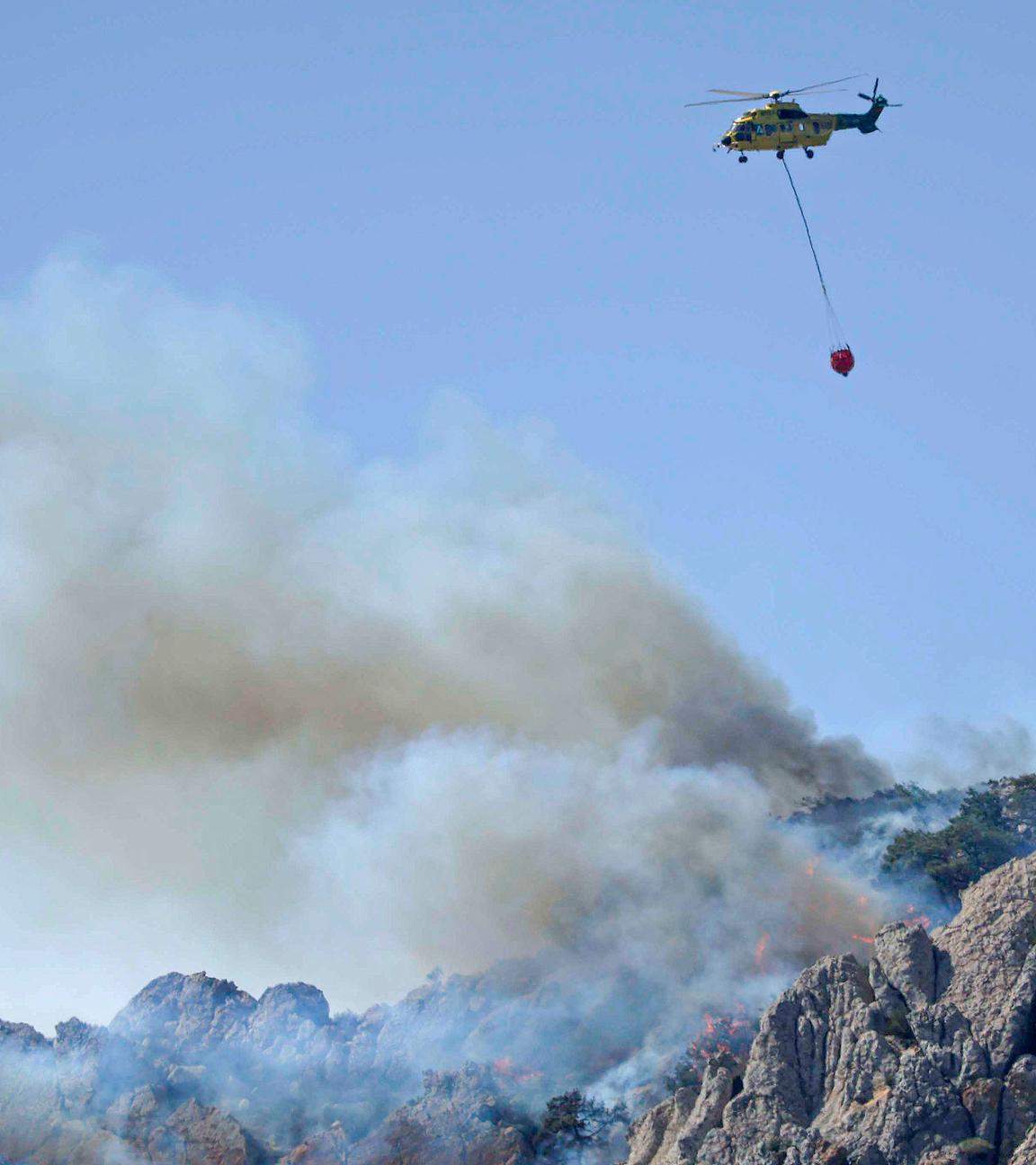 11.08.2025, Spanien, Cadiz: Ein Löschhubschrauber ist während eines Waldbrandes im Einsatz.