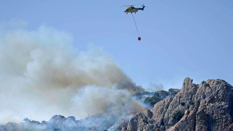 11.08.2025, Spanien, Cadiz: Ein Löschhubschrauber ist während eines Waldbrandes im Einsatz.