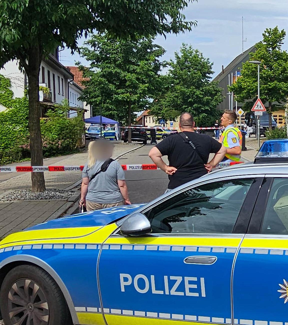Eine Straße ist mit einem Polizeifahrzeug und Polizeiflatterband abgesperrt. In Wangen im Kreis Göppingen ist ein Mann erschossen worden, der zuvor mit einem Messer auf zwei Polizeibeamte zugegangen war.