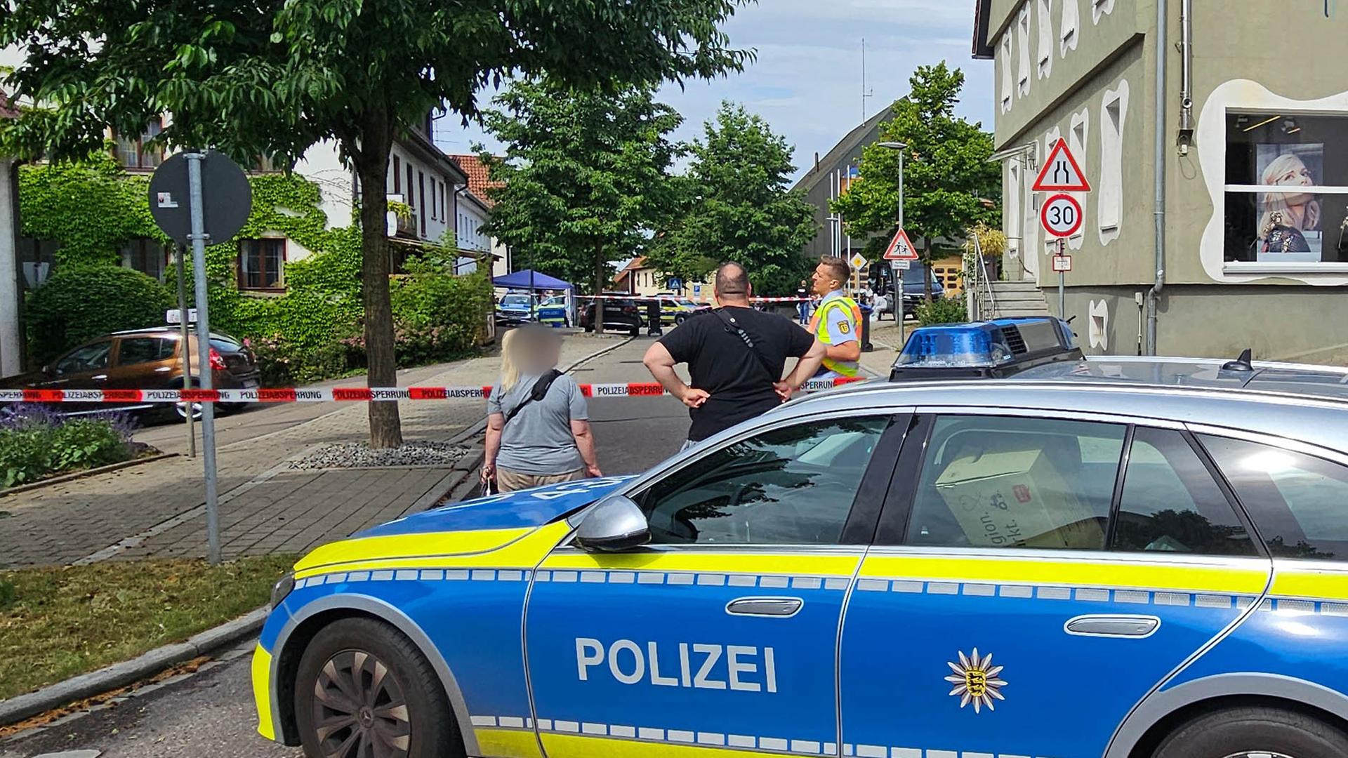 Eine Straße ist mit einem Polizeifahrzeug und Polizeiflatterband abgesperrt. In Wangen im Kreis Göppingen ist ein Mann erschossen worden, der zuvor mit einem Messer auf zwei Polizeibeamte zugegangen war.