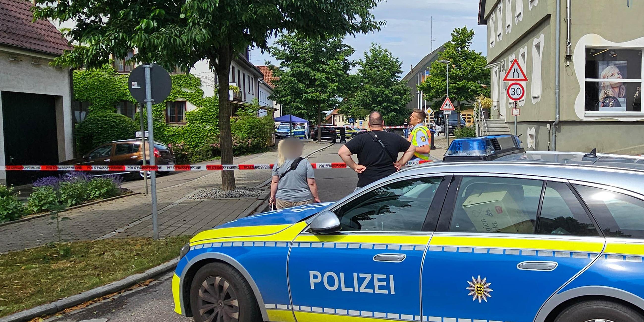 Eine Straße ist mit einem Polizeifahrzeug und Polizeiflatterband abgesperrt. In Wangen im Kreis Göppingen ist ein Mann erschossen worden, der zuvor mit einem Messer auf zwei Polizeibeamte zugegangen war.