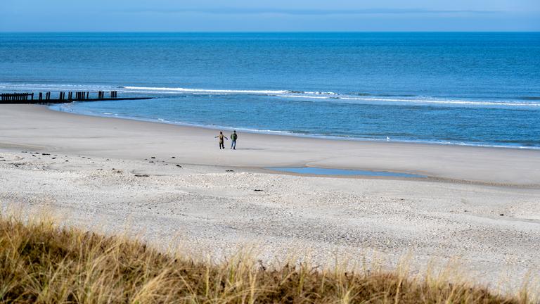 Niedersachsen, Wangerooge: Spaziergänger sind bei sonnigem Wetter am Strand der Insel unterwegs