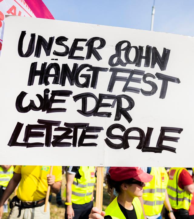 Ein Plakat bei einer Kundgebung zum Warnstreik der Beschäftigen des Einzel- und Großhandels.