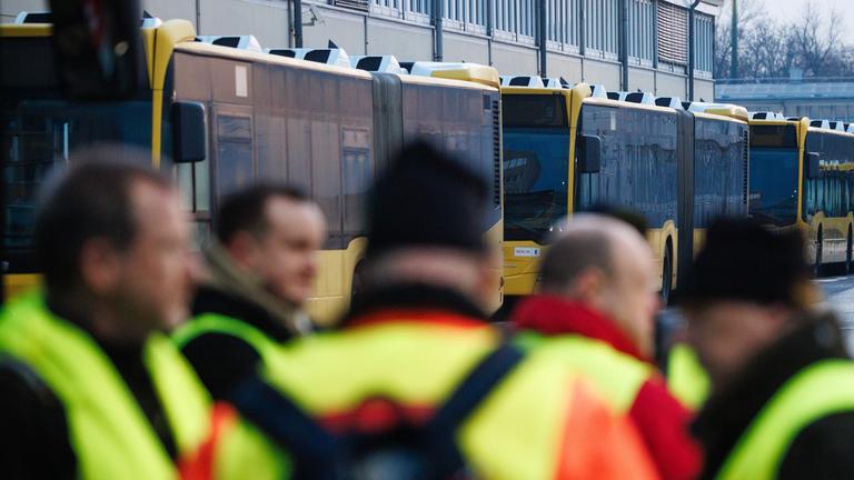 Mitarbeiter mit Warnwesten stehen während eines Warnstreiks im öffentlichen Nahverkehr in Deutschland vor dem BVG-Busdepot Lichtenberg in Berlin am 27. Februar 2026.