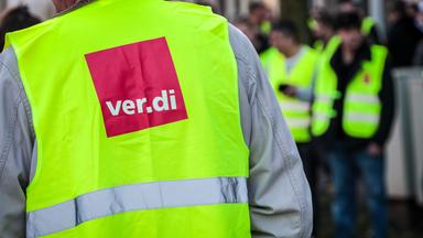 Ein Streikender trägt bei einer Demonstration eine Warnweste der Gewerkschaft Verdi.