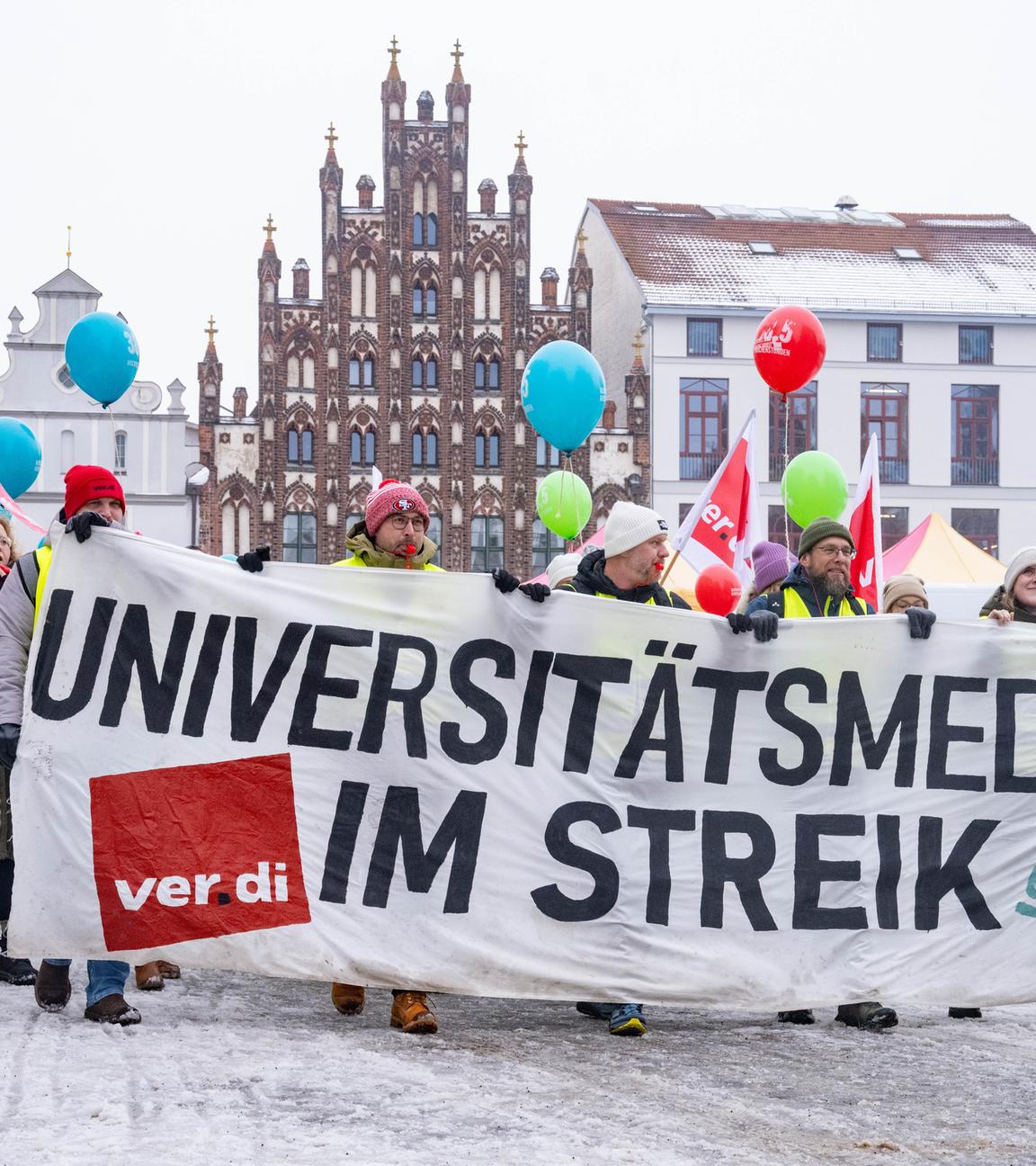 Teilnehmer der Demonstration halten Ballons und tragen ein Banner.
