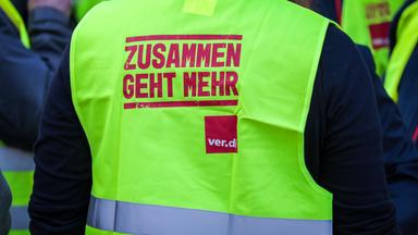 Ein Streikender trägt bei einer Demonstration durch die Innenstadt in Bremen eine Warnweste der Gewerkschaft Verdi.